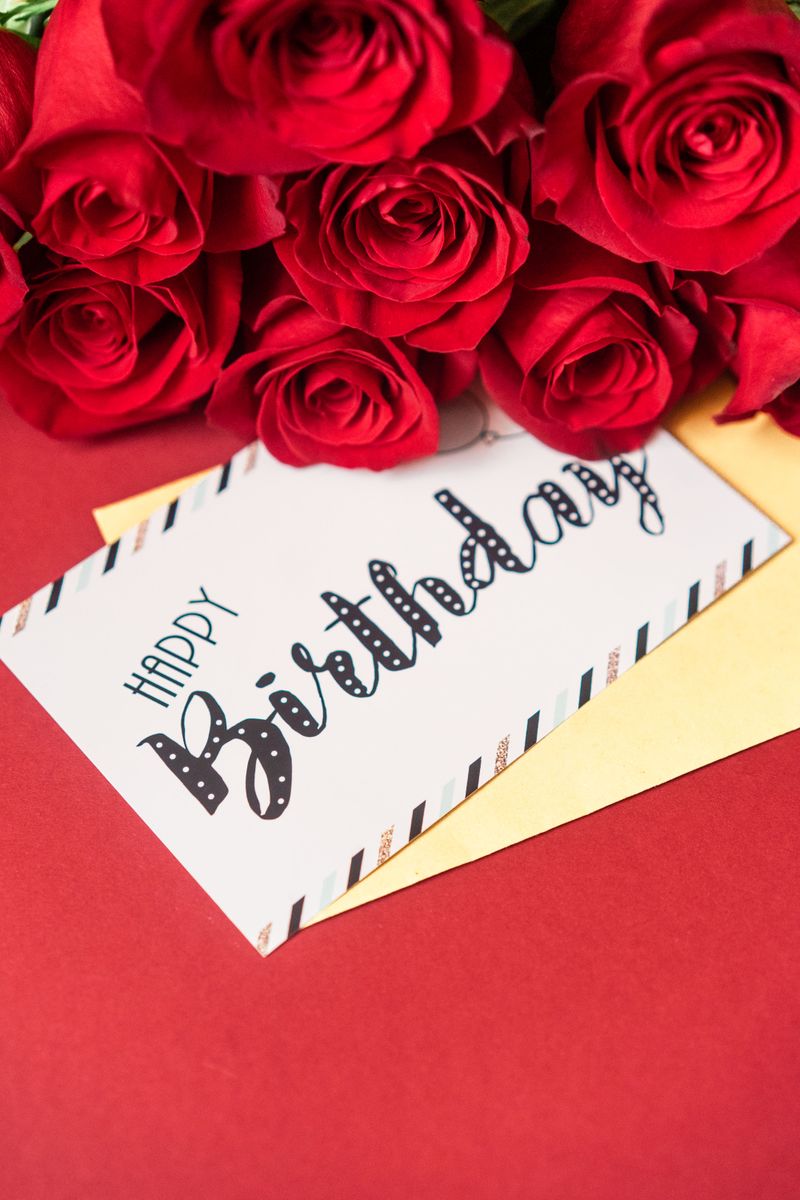 Greeting card and envelope for a birthday, alongside a bouquet of roses