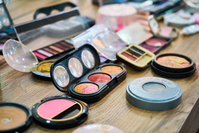 Assorted makeup and cosmetics including eyeshadow palettes and blush compacts